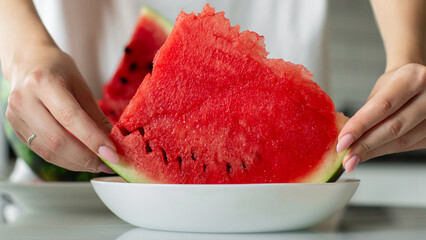 Woman with slice of fresh watermelon at kitchen, closeup