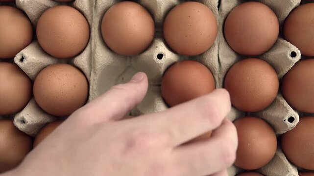 Overhead view of taking eggs from an egg carton. Close up on male hand picking eggs.