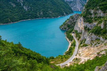 A road in a valley next to a lake surrounded by mountains