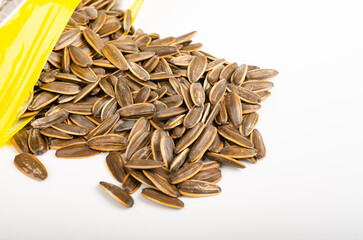 close up roast sunflower seeds pour from bag isolated on white background