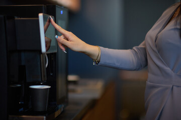 Professional using a touchscreen coffee machine for a convenient coffee break at work