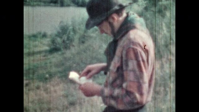 Male treasure hunter looking at map in treasure search. Cowboy in hat discover for coordinates of buried pirate treasure on green nature background. Vintage color film. Retro adventure archive 1960s