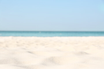 Blurred view of beautiful sandy beach and sea on sunny day. Summer vacation