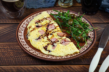 Fried omelet stuffed with sausage. Omelette with arugula and capers