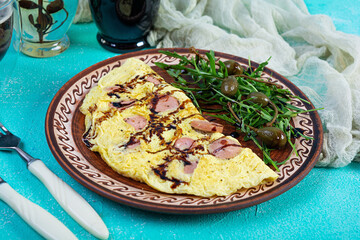 Fried omelet stuffed with sausage. Omelette with arugula and capers