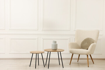 Soft armchair, coffee tables and lamp in light room