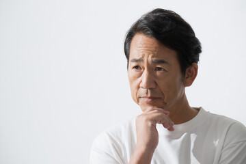 顎に手を当てるシニア男性　50代の美容やスキンケアのイメージ