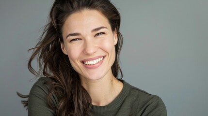 Fototapeta premium Portrait of a Woman With Long Brown Hair Smiling Against a Gray Background