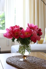 Beautiful pink peonies in vase on wooden table indoors