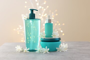 Cosmetic products and beautiful jasmine flowers on grey table