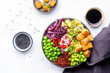 Vegan Buddha Bowl for balanced diet with tofu, quinoa, vegetables, legumes, seeds and sprouts. White table background, top view