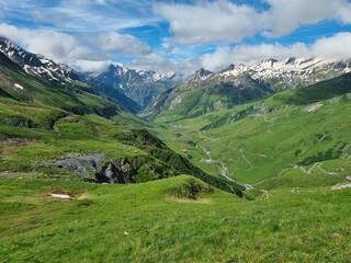 The Tour du Mont Blanc trail, TDMB, leading across lush green mountain meadow with full view of the snow covered Mont Blanc massif in summer in the Chamonix valley in France
