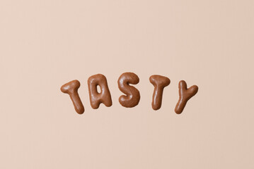Sweet composition with the word Tasty on a beige background. Alphabet biscuits on a pastel background