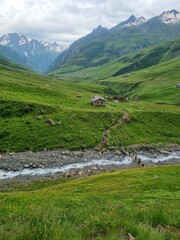 The Tour du Mont Blanc trail, TDMB, leading across lush green mountain meadow with full view of the snow covered Mont Blanc massif in summer in the Chamonix valley in France

