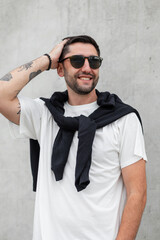 Happy handsome young successful man with a smile with sunglasses in a white fashion T-shirt with a...