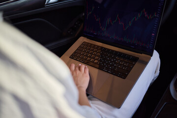 Fototapeta premium A person is working on a laptop inside a car during their commute to a destination
