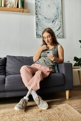 A young woman with a prosthetic leg sits on a couch in her living room, surprised by something she...