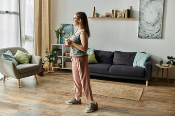 Obraz premium A young woman with a prosthetic leg stands in her living room, looking out the window.