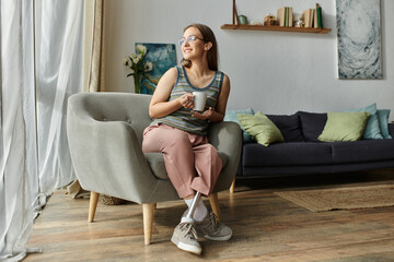 A woman with a prosthetic leg enjoys a warm drink in her living room as sunlight filters through...