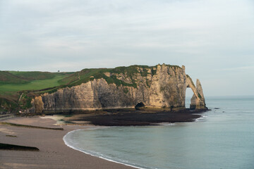 Sunrise or sunset at the empty beach of Etretat with the cliff with an arch view. Tranquil and...
