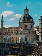 Obraz premium A large building with a dome on top and a tall column. The building is surrounded by other buildings and a street