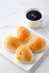 焼きたてで熱々のバターロールと、淹れたてで香りのよいコーヒーが用意された朝食のテーブル
