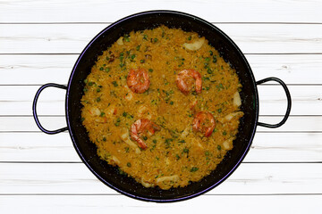 Iron dish with homemade Spanish paella, featuring traditional ingredients.