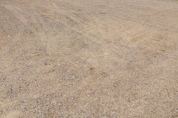 Gravel road from the texture of fine stones. Dirt road background with car tire prints
