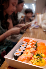 A plate of delicious assorted Japanese salmon sushi with children sitting on the background at a restaurant