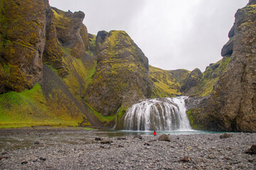 person sitting in front of a tranquil waterfall on a cloudy day in Iceland