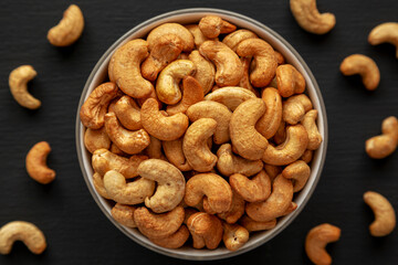 Roasted Organic Cashews in a Bowl on a black background, top view.