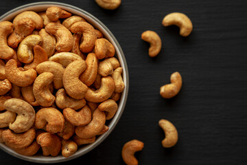 Roasted Organic Cashews in a Bowl on a black background, top view.