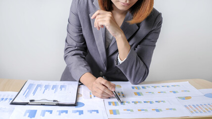 Asian businesswoman sit at their desks and calculate financial graphs showing results about their...