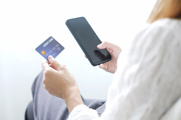 Asian girl shopping online holding credit and using smartphone enter their card number in the mobile phone app to purchase and payment in internet store