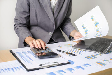 Asian businesswoman sit at their desks and calculate financial graphs showing results about their...