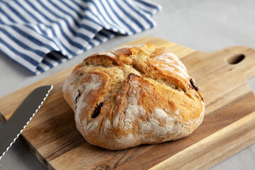 Homemade Bread with Kalamata Olives on a wooden board, side view.