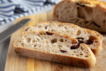 Homemade Bread with Kalamata Olives on a wooden board, side view.