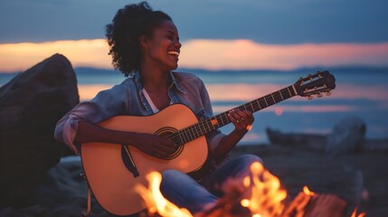An African American black woman, girl playing a guitar at the beach and singing a song next to a camping fire. Picnic or party with friends and vacation by the sea. Romantic summer evenings on travel