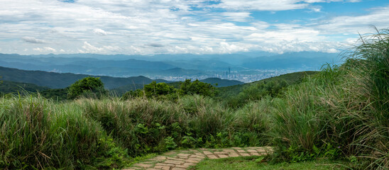 Naklejka premium Walking trails in the grasslands of Yangmingshan National Park, with the city of Taipei in the distant background, Taiwan