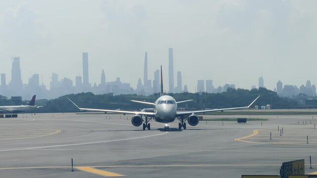An airplane taxiing to the gate at New York City's LaGuardia Airport. The skyline of Manhattan in the far distance. Aircraft's identifiable markings digitally removed.  	