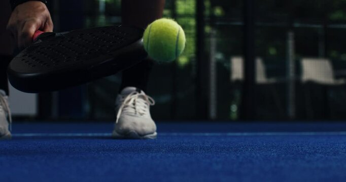 Super slow motion macro of paddle player is serving ball during competition game match or training workout on indoor court at 1000 fps.