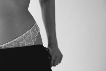 A girl puts on panties and underwear, beautiful delicate black white fashion photograph on a white background. A woman in lingerie and panties, a woman with beautiful hands
