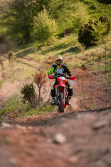 Obraz premium Professional enduro bike rider on action, dirt ride on the muddy road. Motocross sport.