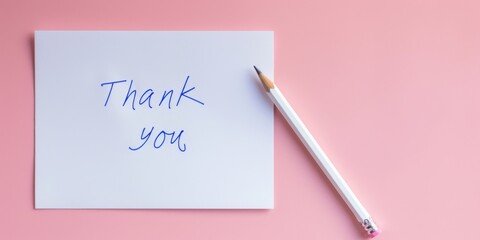 White card with blue ink handwritten thank you message and pencil on pink background, top view banner with copy space