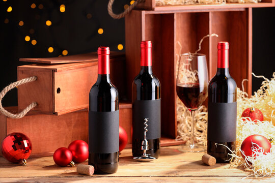 Bottles of wine, glass, wooden boxes, corks and red Christmas balls on table