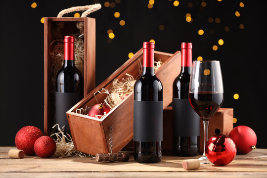 Bottles of wine, glass, wooden boxes, corks and red Christmas balls on table