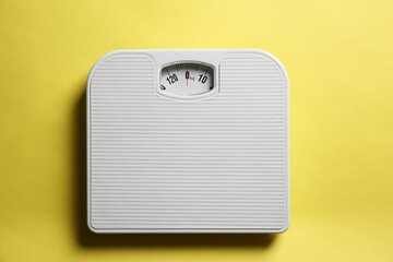 One bathroom scale on yellow background, top view