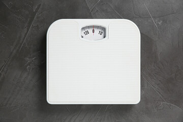 One bathroom scale on grey textured background, top view