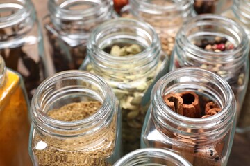 Different spices in glass jars on table, closeup