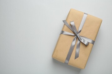 Gift box with satin bow on grey background, top view. Space for text